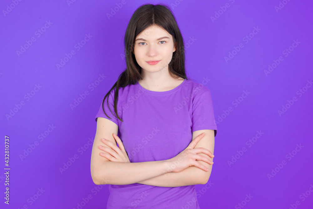 Obraz premium Self confident serious calm young beautiful Caucasian girl wearing purple T-shirt over purple background stands with arms folded. Shows professional vibe stands in assertive pose.