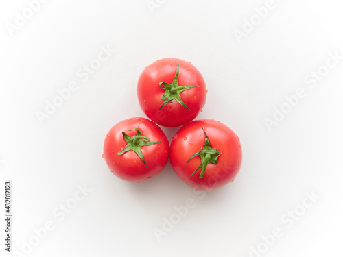 Three ripe tomatoes on a light gray ceramic surface. Top view. Not isolated © RISHAD