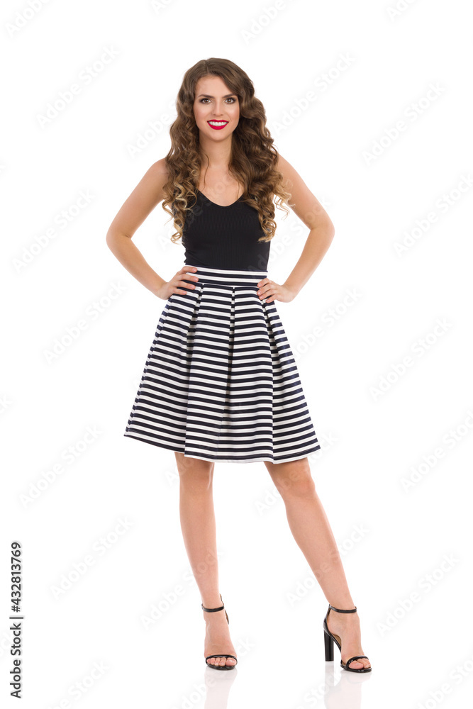 Young Woman In Striped Skirt And High Heels Is Standing With Hands On Hip Young Woman In Striped Skirt And High Heels Is Standing With Hands On Hip