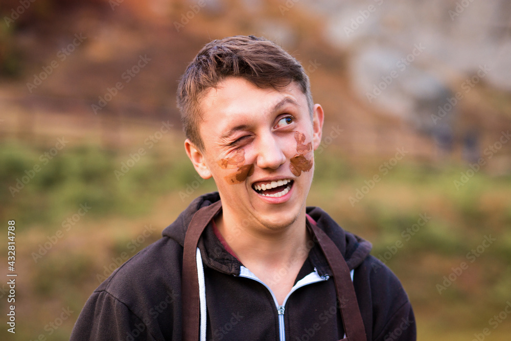 Joyful portrait of man potter with clay dirty face. Young handsome man on pottery workshop of ceramic for children. Hobby and leisure concept Joyful portrait of man potter with clay dirty face. Young handsome man on pottery workshop of ceramic for children. Hobby and leisure concept