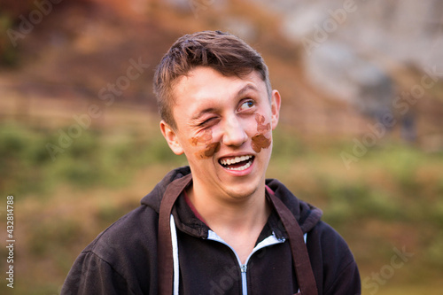 Joyful portrait of man potter with clay dirty face. Young handsome man on pottery workshop of ceramic for children. Hobby and leisure concept