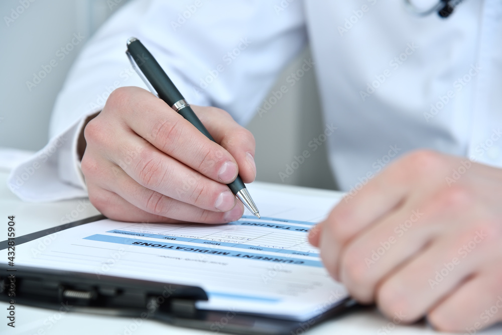 Fototapeta premium Doctor hands writing on clipboard in medical office