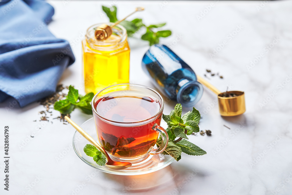 Black tea in glass transparent mug with mint leaves and honey. Calming and revitalizing tea, anti-stress and relaxation Black tea in glass transparent mug with mint leaves and honey. Calming and revitalizing tea, anti-stress and relaxation