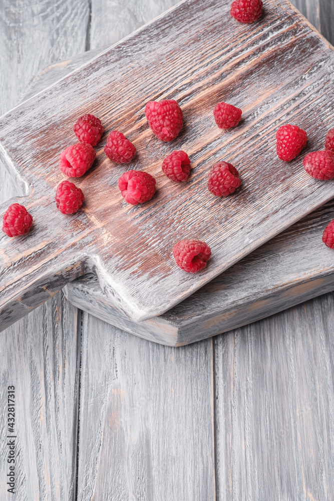 Raspberry fruits on old cutting board, healthy pile of summer berries on grey wooden background, angle view Raspberry fruits on old cutting board, healthy pile of summer berries on grey wooden background, angle view