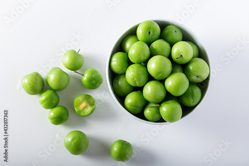 Fresh green plums in a white bowl. Top view. photo