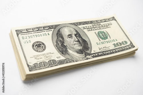 A money pile of stacked one hundred US banknotes with president Franklin portrait on white background. Cash of hundred dollar bills, paper money currency.