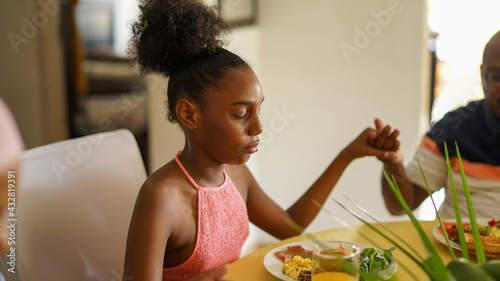 Young girl praying at breakfast table