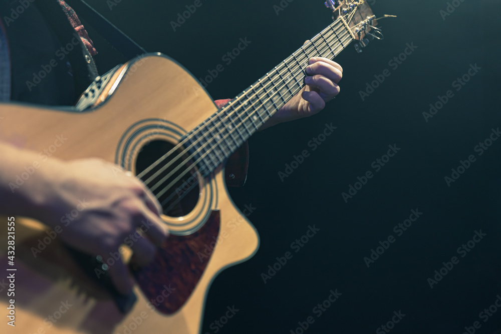 Fototapeta premium Guitarist playing acoustic guitar in the dark.