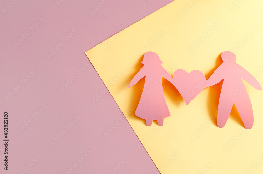 Bright red figures of two people and a heart on a red and yellow background of kopi space. The concept of a happy relationship. Cardboard figures of people and hearts. Bright red figures of two people and a heart on a red and yellow background of kopi space. The concept of a happy relationship. Cardboard figures of people and hearts.