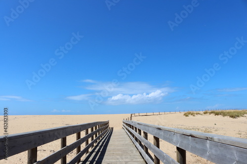 Long Wooden bridge leading to the sandy beach and the Atlantic Ocean. Portugal beaches.