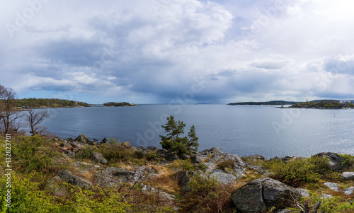 Dramatic spring weather with sun and dark rain clouds over the sea in Karlshamn  Sweden. Panoramic view.