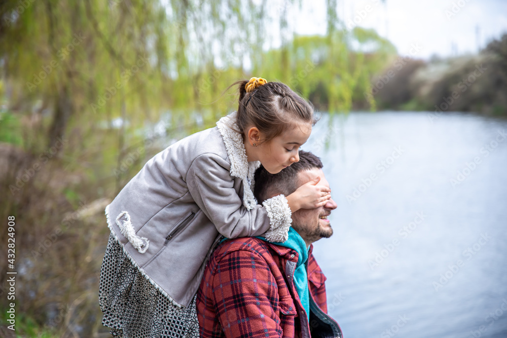 A little girl with her dad for a walk in the woods are sitting by the river. A little girl with her dad for a walk in the woods are sitting by the river.