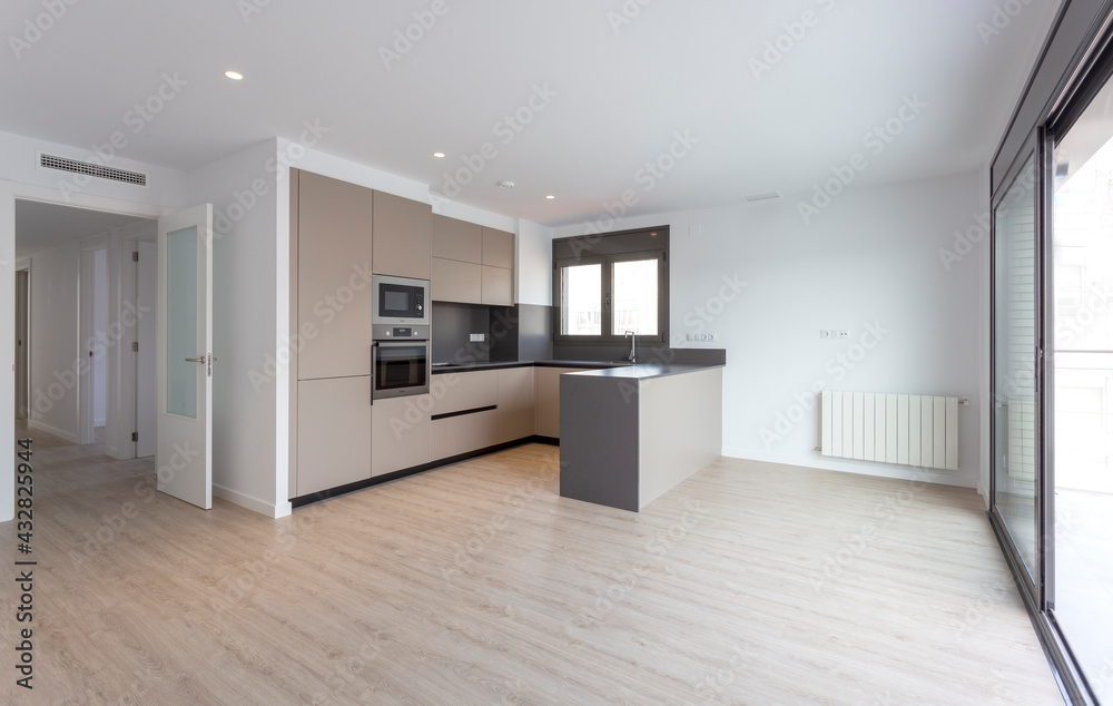 Barcelona, Spain. 9-25-2019. An empty brown kitchen of a brand new apartment with a big window sold by a real estate. Barcelona, Spain. 9-25-2019. An empty brown kitchen of a brand new apartment with a big window sold by a real estate.