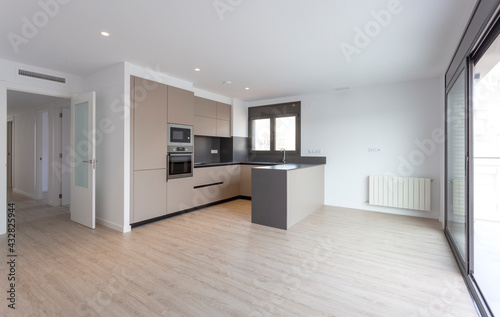 Barcelona, Spain. 9-25-2019. An empty brown kitchen of a brand new apartment with a big window sold by a real estate. photo