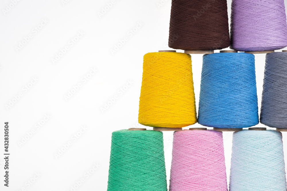 Spools of multicolored cotton thread on a white background lined up in a pyramid with space for text Spools of multicolored cotton thread on a white background lined up in a pyramid with space for text