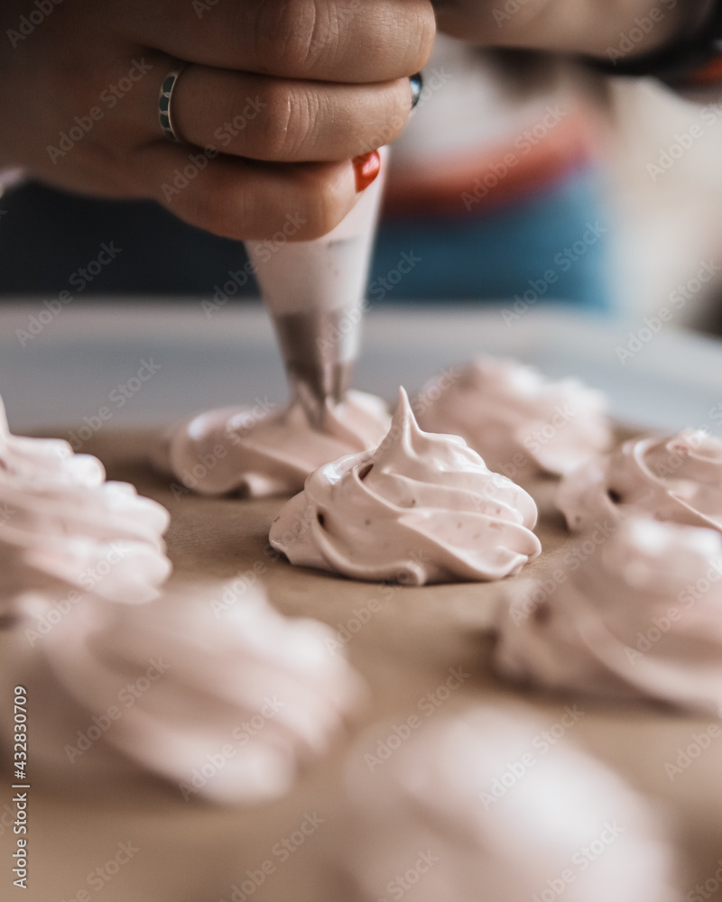 Girl squeezes out cream roses, meringues, marshmallows on a baking sheet from a pastry bag. Desserts, cooking cover