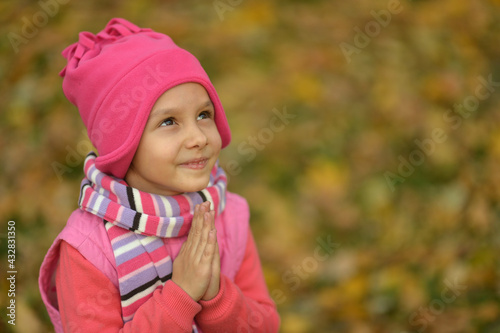 Cute little girl in an autumn park praying