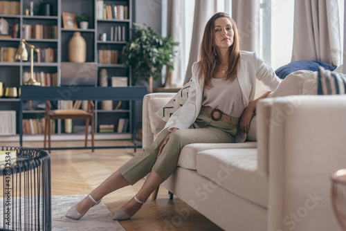 Woman in business attire after work at home resting on couch.