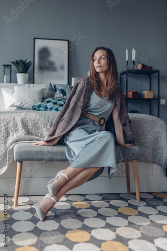 Woman at home in bedroom sitting on bedside bench. photo