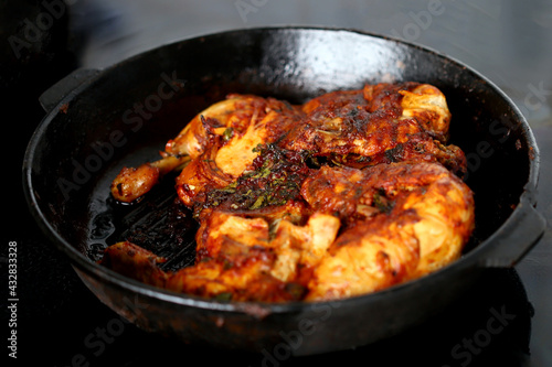 Appetizing grilled chicken in a cast-iron skillet. Delicious chicken with a golden-brown crust.