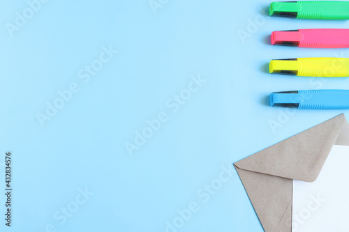 Craft a conver with a white sheet of paper and multicolored markers on a blue background with a copy space, a view from above. Workspace. photo