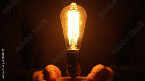 Photographie Man is holding an Edison light bulb.