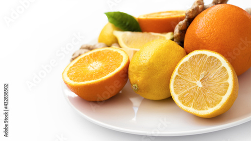 citruses on a white plate, oranges, lemons and ginger on a white plate on a white background.
