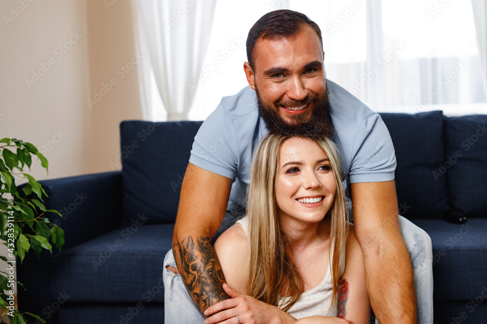 Fototapeta premium Happy smiling couple sitting on blue sofa in living room