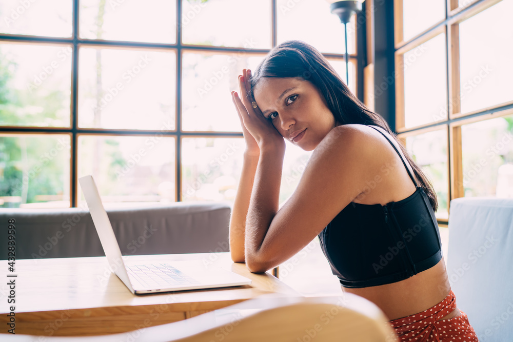 Obraz premium Tired young ethnic employee using laptop in creative workspace