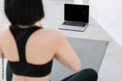 Asian young sporty slim woman coach internet video online training oga instructor modern laptop screen meditate relax breathe easy seat pose gym healthy lifestyle concept.