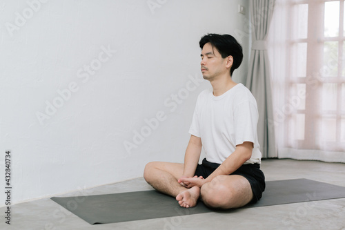 Asian young man doing yoga at home