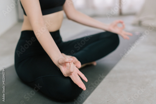 Young healthy beautiful asian woman in sportive top and leggings practicing yoga at home sitting on yoga mat relaxed, yoga concept