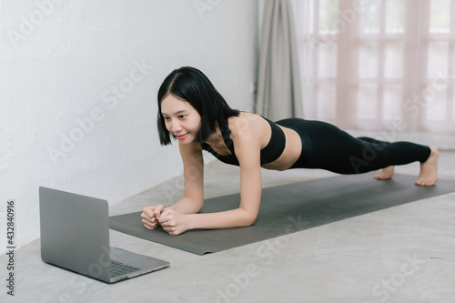 Girl training at home, exercising and watching videos on laptop, training in living room