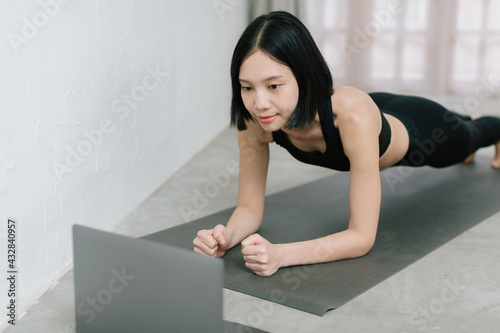 Girl training at home, exercising and watching videos on laptop, training in living room