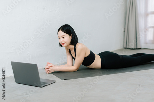 Girl training at home, exercising and watching videos on laptop, training in living room