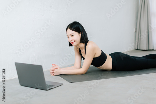 Girl training at home, exercising and watching videos on laptop, training in living room