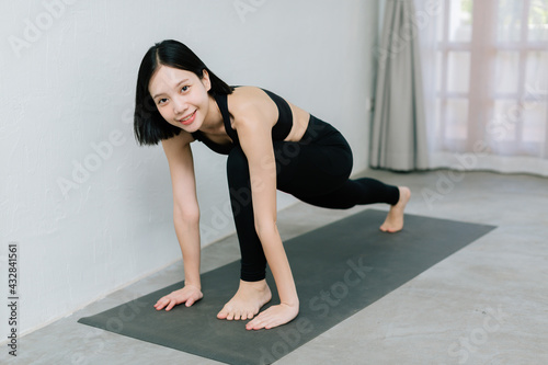 Young asian woman doing sport exercises indoor at home