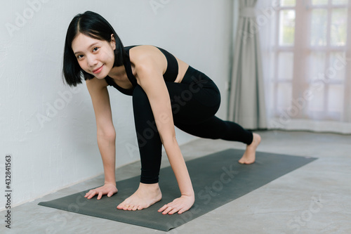Young asian woman doing sport exercises indoor at home