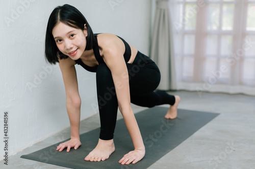 Young asian woman doing sport exercises indoor at home