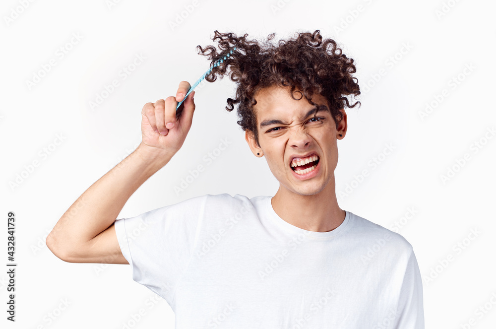 emotional guy with curly hair combing hair light background emotional guy with curly hair combing hair light background