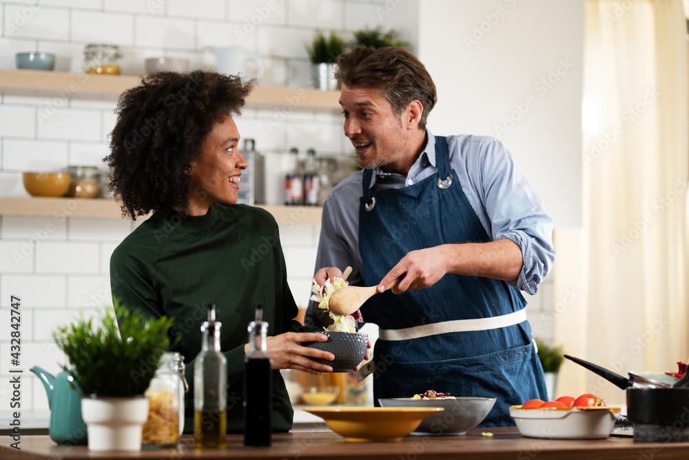 Happy smiling couple cooking together. Husband and wife preparing delicious food Happy smiling couple cooking together. Husband and wife preparing delicious food