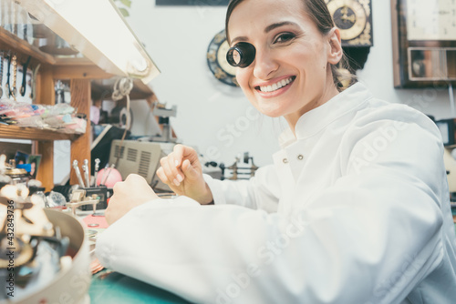 Watchmaker woman looking at camera in her workshop photo