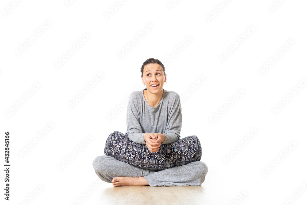 Restorative yoga with a bolster. Young sporty female yoga instructor sitting in bright white yoga studio holding bolster cushion showing love and passion for restorative yoga Restorative yoga with a bolster. Young sporty female yoga instructor sitting in bright white yoga studio holding bolster cushion showing love and passion for restorative yoga