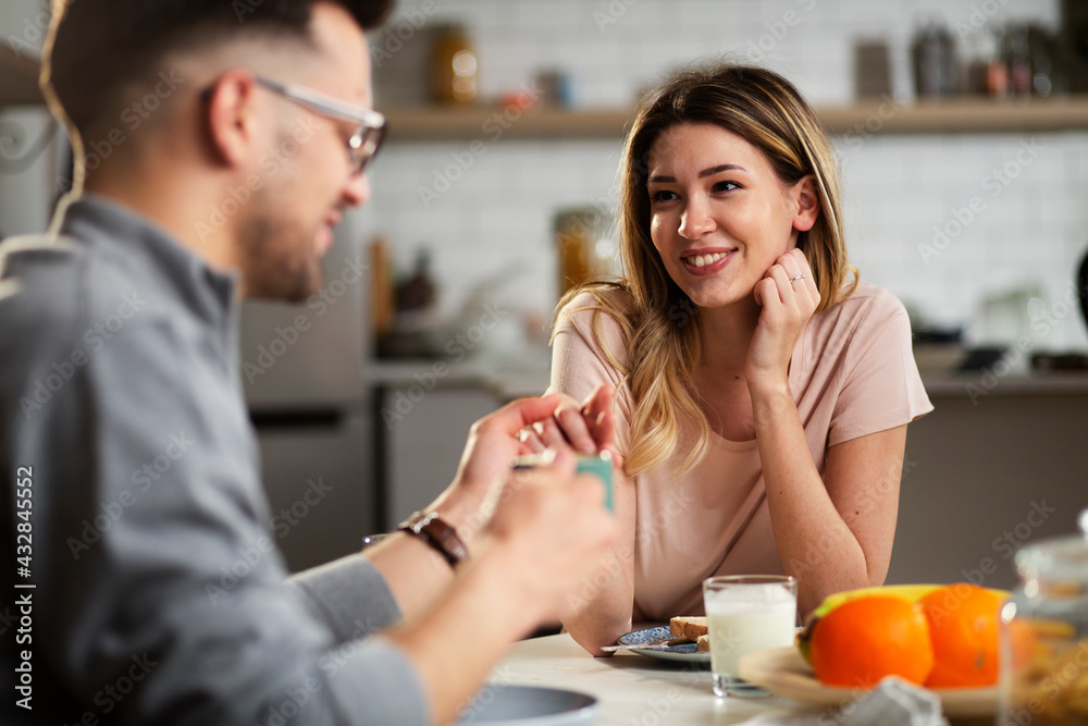 Beautiful young girl enjoying in breakfast with her boyfriend. Loving couple drinking coffee in the kitchen.. Beautiful young girl enjoying in breakfast with her boyfriend. Loving couple drinking coffee in the kitchen..