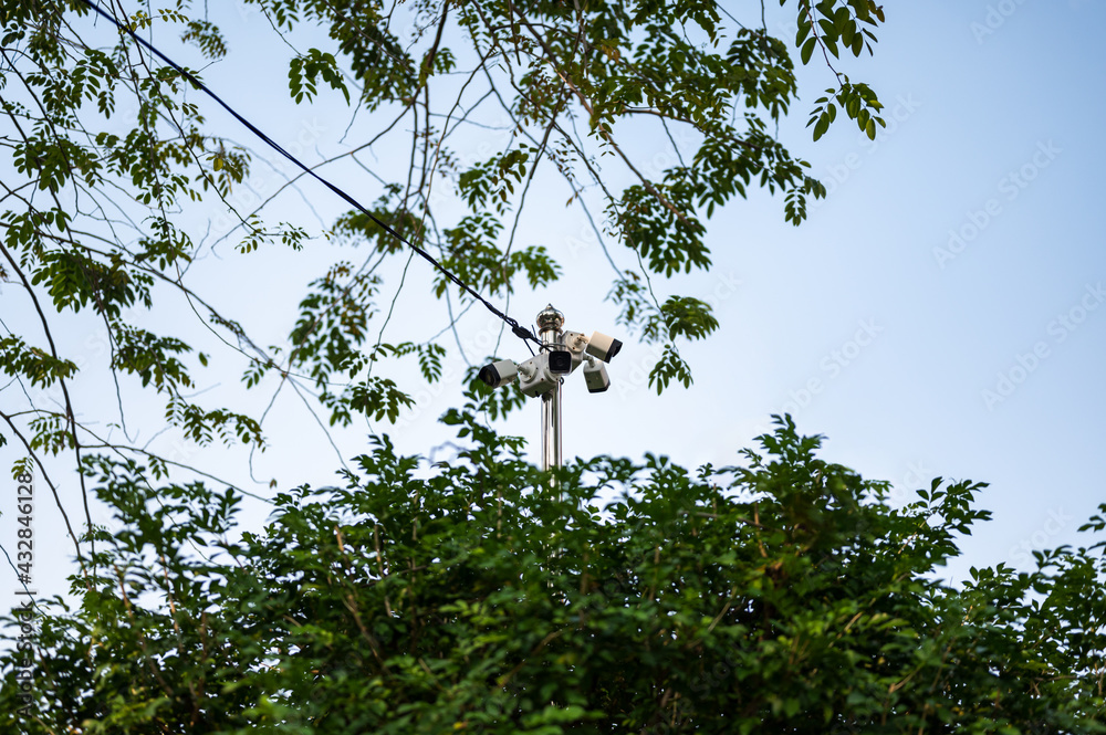 4 CCTV cameras on stainless steel posts High above the treetops with a bright sky background. 4 CCTV cameras on stainless steel posts High above the treetops with a bright sky background.