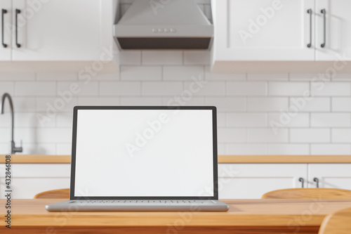 Modern laptop with white blank mockup screen on the dining table at cozy kitchen.
