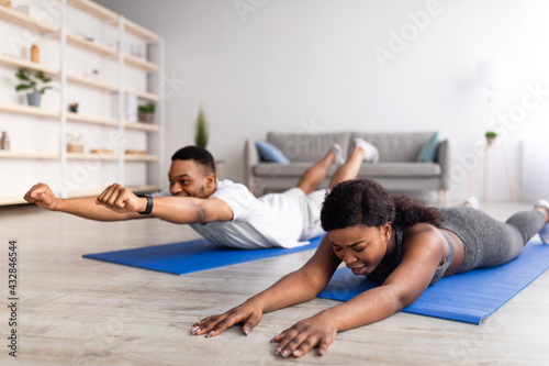 Young black woman feeling tired during yoga practice with her boyfriend at home