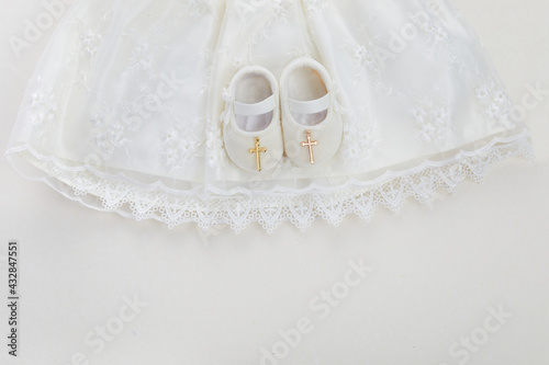 Obraz na plátně Christening background with baptism baby dress, shoes, and cross on pastel backg