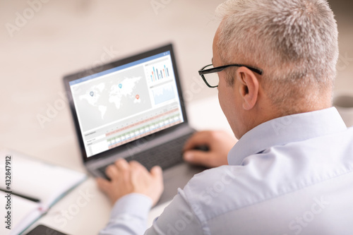 Senior businessman using laptop, checking stock analysis software