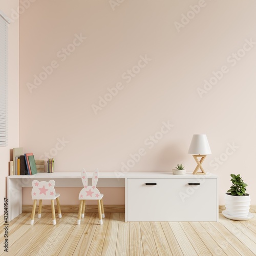 Children's room with cream colored walls is blank. There were books, colored pencils and lamps on the table and a chair and a tree on the floor.3d rendering.